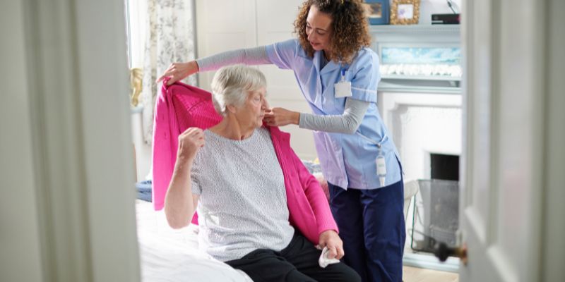 nurse putting jacket on resident