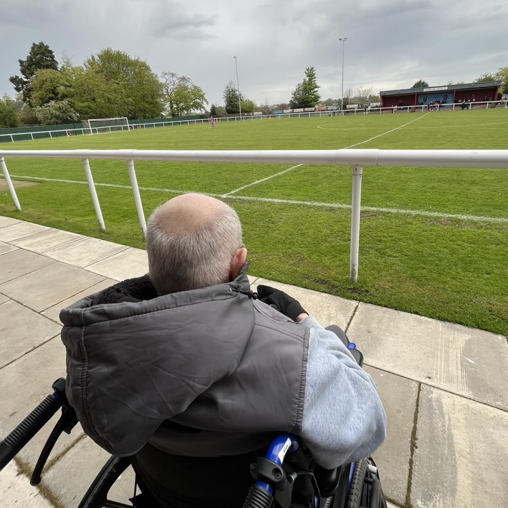 older man sat in a wheelchair watching a football game