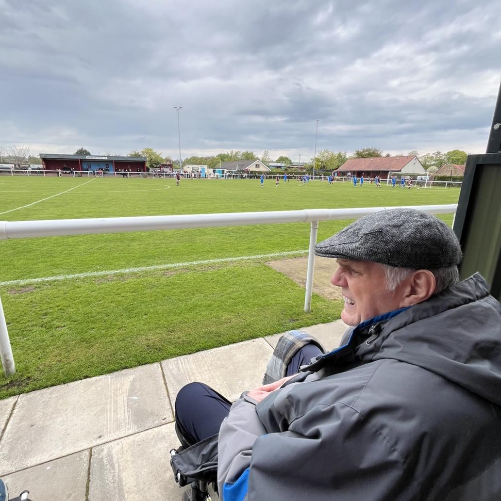 older man sat in a wheelchair watching a football game