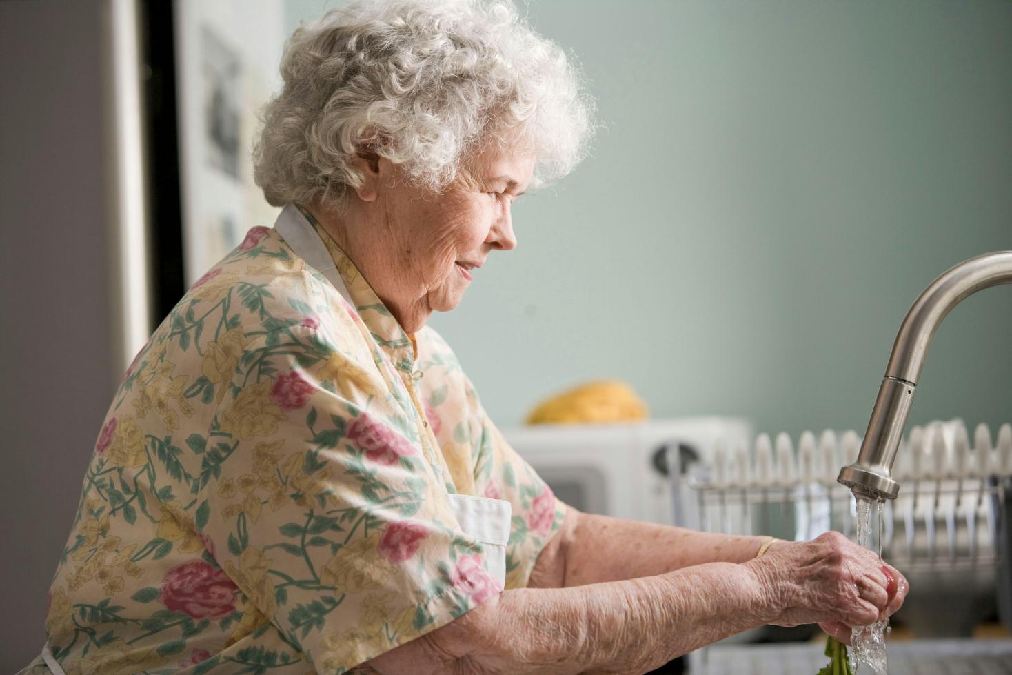 elderly woman using a kitchen sink